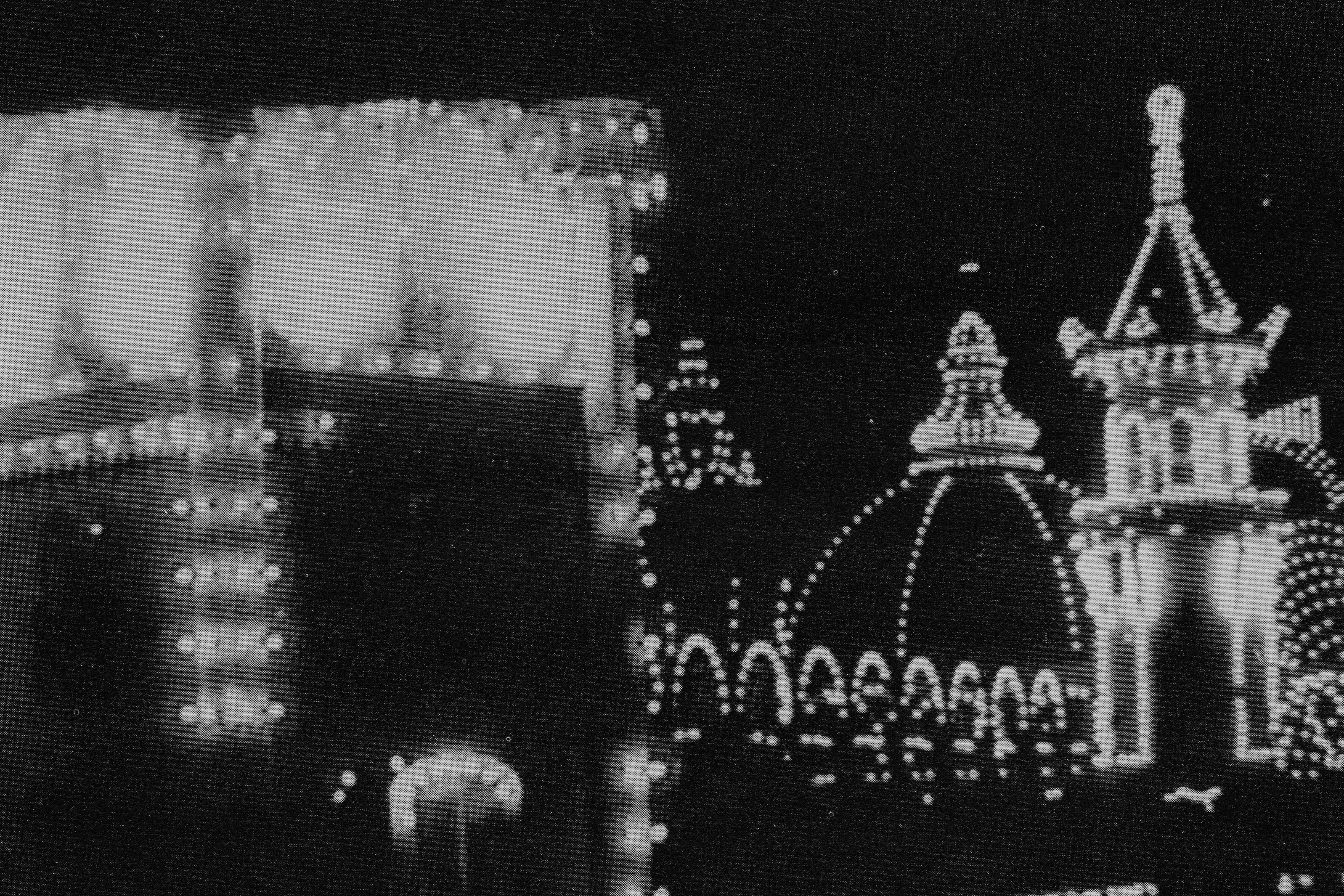 A black and white image of Coney Island at night. A black and white image of Coney Island at night.